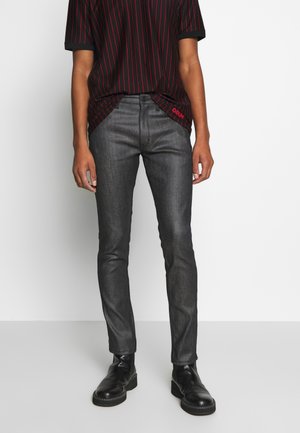 Jeans de denim oscuro con un corte ajustado, que presentan una textura suave. Combinados con una camiseta de rayas negras y botas negras.