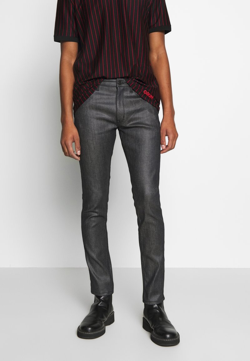 Mörk denimjeans med slim fit, som har en slät textur. Kombinerat med en svart randig T-shirt och svarta stövlar.