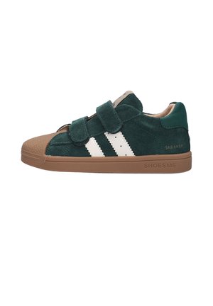 Groene suède sneaker met twee witte strepen, bruine rubberen zool en neuskap, en twee klittenbandsluitingen aan de zijkant.
