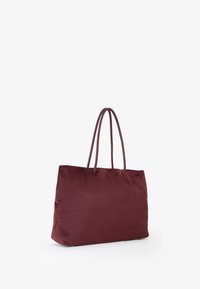 Borsa a tracolla bordeaux con doppio manico, realizzata in tessuto morbido e liscio, con una forma rettangolare e senza hardware o motivi visibili.