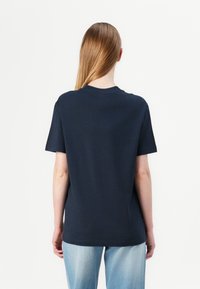 Námořnická modrá bavlněná trička s krátkým rukávem, kulatým výstřihem a volným střihem. Jednoduchý design, bez viditelných vzorů nebo grafiky.