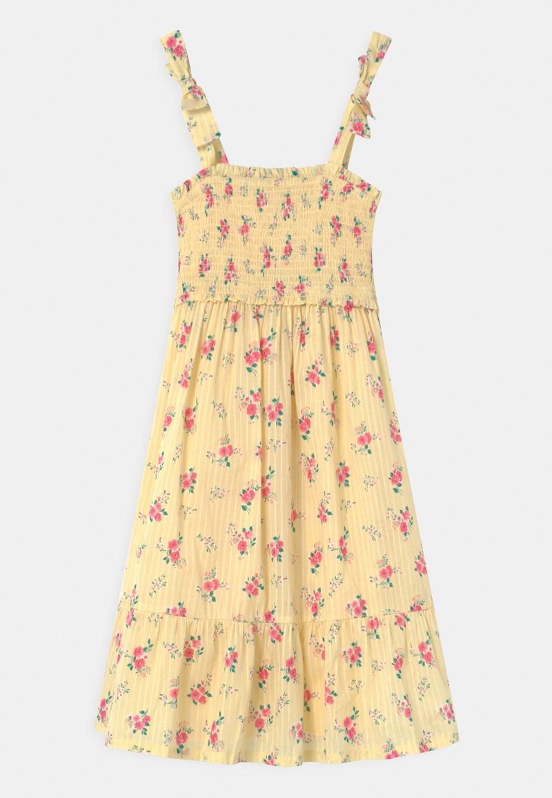 Robe d'été jaune sans manches avec imprimé floral rose, corsage smocké, bretelles nouées et ourlet à volants.