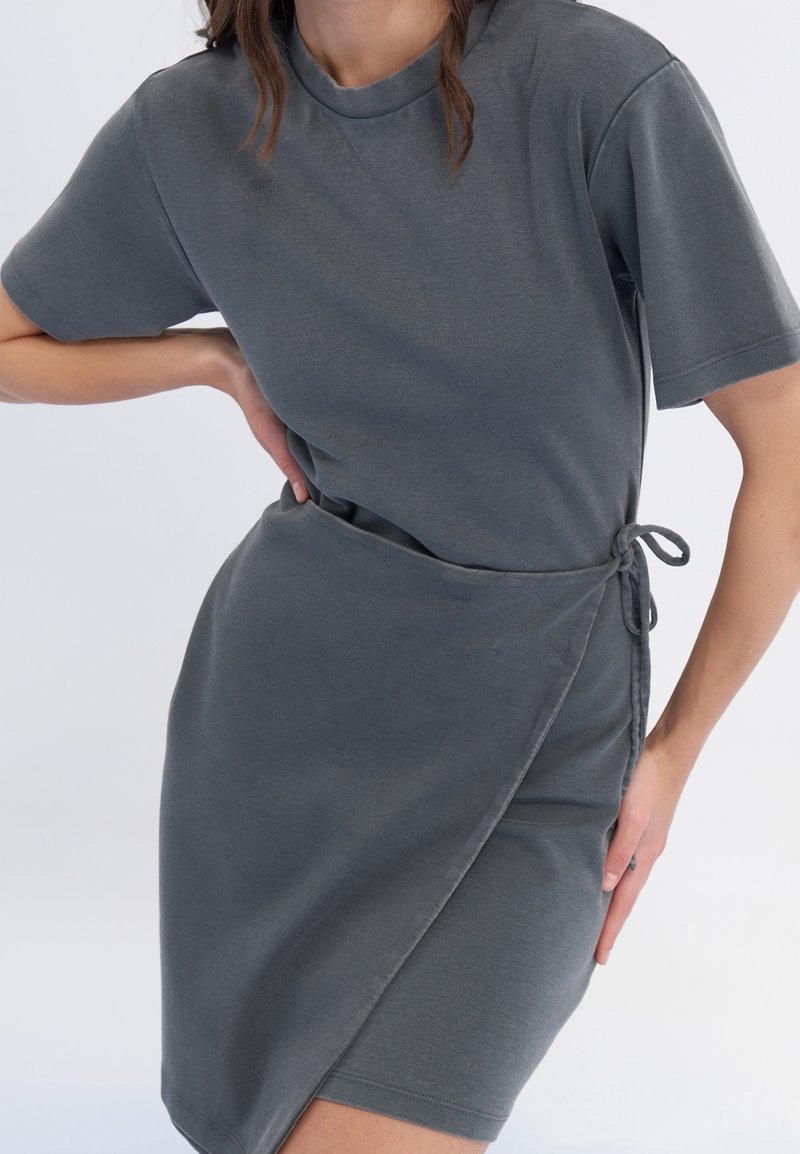 Robe grise à manches courtes avec un design croisé, lien ajustable à la taille et texture douce. Silhouette simple et élégante.