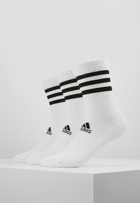 Weiße Sportsocken mit gerippter Textur, die oben drei schwarze Streifen und ein schwarzes Logo an der Seite haben.