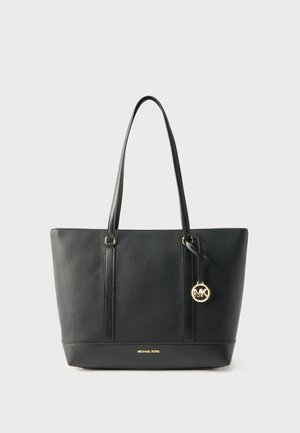 Borsa tote in pelle nera con manici lunghi, logo Michael Kors in oro al centro in basso, e ciondolo rotondo MK in oro appeso al manico.