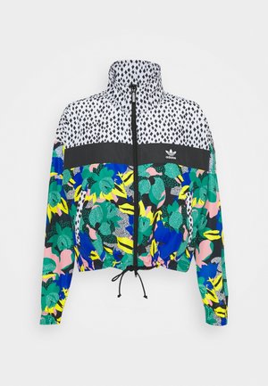 Veste zippée colorée Adidas avec col montant, fermeture éclair noire, bande noire avec logo et motifs floraux et géométriques multicolores.