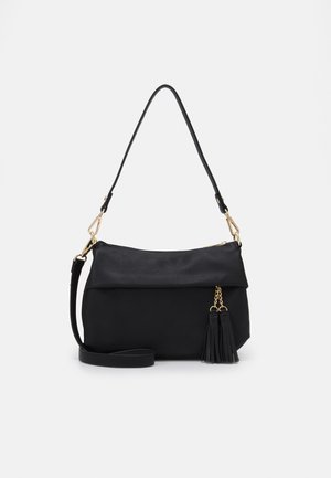 Czarna torba na ramię ze złotymi okuciami, odpinanymi paskami i dwoma czarnymi chwostami wiszącymi na złotym łańcuszku na jednolitym tle.