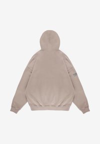 Przesadnie duża beżowa bluza z gładką teksturą, z kapturem na sznurku i ściągaczami przy rękawach. Posiada małe logo na lewym rękawie.