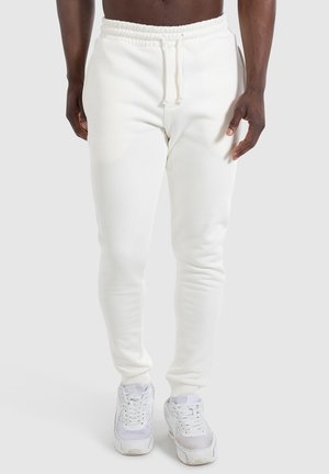 Witte fleece joggingbroeken met een trekkoord in de taille, slim fit ontwerp en geribde enkelmanchetten, gecombineerd met witte sneakers.