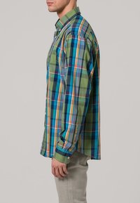 Geverfde overhemd in blauw, groen en oranje tinten met lange mouwen, knoopmanchetten en een enkele borstzak. Katoenen materiaal.