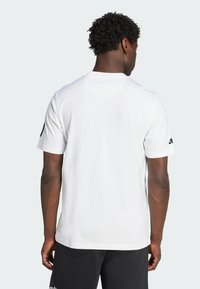 White short-sleeve t-shirt with a crew neck, featuring a smooth texture and black logo accents on the sleeves. Minimalist design.