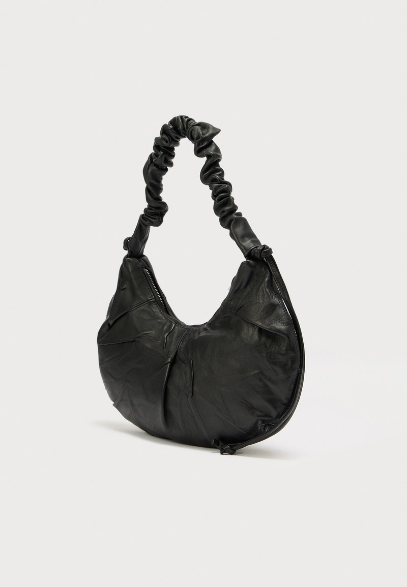 Zwarte leren tas met een afgeronde vorm en een gestructureerde afwerking. Voorzien van een samengevouwen handvat en een ritssluiting aan één zijde.