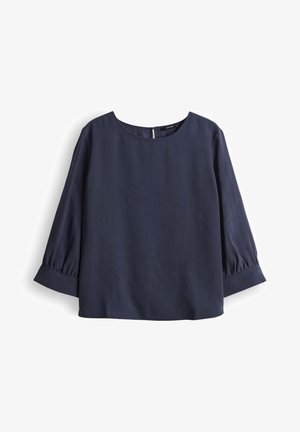 Blouse bleu marine à manches bouffantes trois-quarts, col rond et fermeture par boutons au niveau de la nuque.