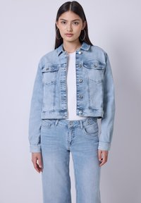 Giacca di jeans azzurro chiaro con design cropped, chiusura a bottoni, due tasche frontali e maniche lunghe. Abbinata a jeans azzurro chiaro coordinati.
