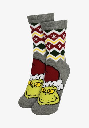 Calzini grigi con la faccia del Grinch verde che indossa un cappello di Babbo Natale rosso, con motivi a zigzag e stelle rossi, bianchi, gialli e verdi sul risvolto.