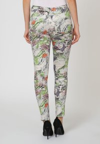 Pantalones con estampado floral que presentan patrones vibrantes en verde, naranja y púrpura sobre un fondo claro. Diseño ajustado y de longitud hasta el tobillo.