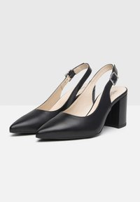 Chaussures noires en cuir à bride arrière avec un bout pointu, un talon bloc et une sangle réglable à la cheville. Texture lisse et design minimaliste.