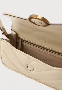 Beige δερμάτινη τσάντα ώμου με καπιτονέ σχέδιο, κλείσιμο με μαγνητικό καπάκι, χρυσό φερμουάρ εσωτερικής τσέπης και αποσπώμενο λουρί.