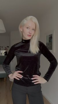 Fekete, hosszú ujjú, testhezálló felső, fényes anyagból, magas nyakkal. Finom csillogással és sima textúrával rendelkezik. Fekete nadrággal párosítva.