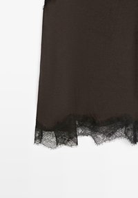 Dark brown fabric with a scalloped black lace trim featuring floral patterns along the edge on a white background.
