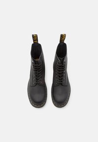 Stivaletti neri in pelle con punta tonda, lacci davanti e suola cucita in giallo. Include un pratico gancio di tiraggio giallo sul retro.