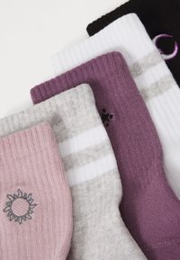 Multicolored socks: pink with sun embroidery, grey striped, solid purple, white with grey stripes, and solid black. Knit textures visible.