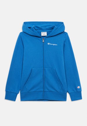 Blå Champion hettejakke med glidelås, frontlommer, hette og hvit logo på brystet og ermekanten, lagt flatt på hvit bakgrunn.