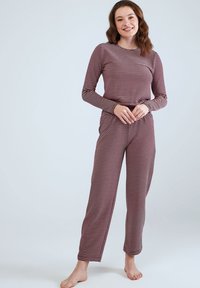 Langsleeve rood-wit gestreepte pyjama-top met bijpassende broek. Zacht materiaal, ontspannen pasvorm en subtiele textuur. Geen zichtbare logo's of versieringen.