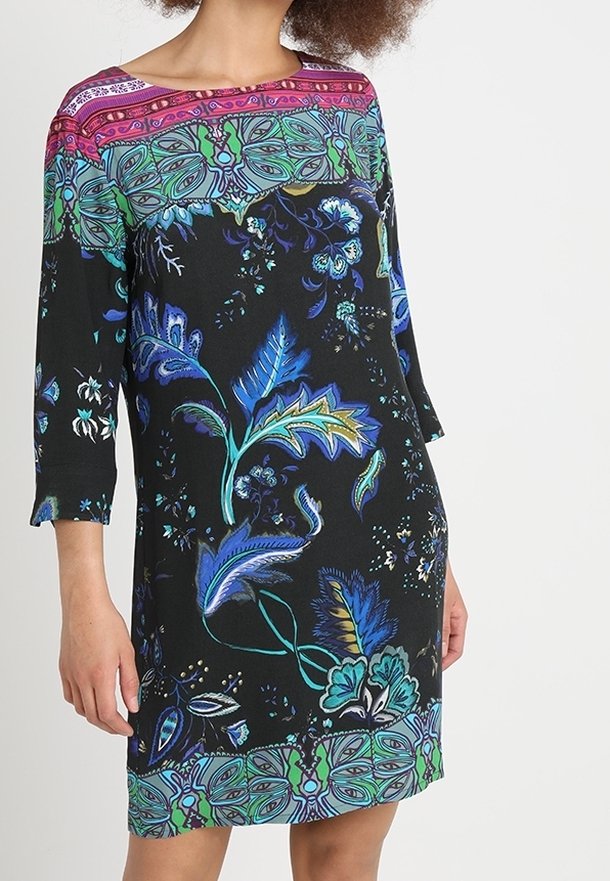 Vestido negro con patrones florales en azul y verde, mangas 3/4, y un detalle de escote con un patrón colorido. Textura de tela suave.