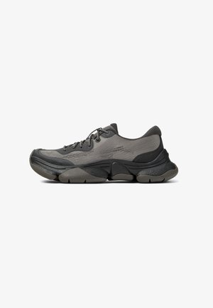 Gray athletic shoe with a mesh upper, padded collar, thick sole, and textured accents. Features round laces and a rounded toe design.