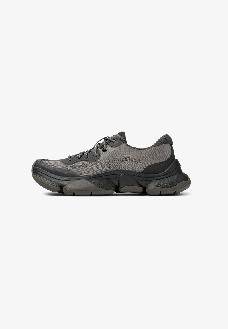 Scarpa sportiva grigia con tomaia in rete, colletto imbottito, suola spessa e dettagli testurizzati. Presenta lacci tondi e un design della punta arrotondato.