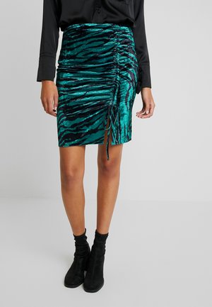 Teal fluwelen rok met zwart tijgerstrepenpatroon, geplooide details en trekkoord aan de zijkant. G gedragen met zwarte enkellaarsjes en een zwarte blouse.