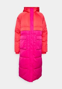 Manteau rembourré long dans des nuances de rouge et de rose, avec une capuche, deux poches avant et une fermeture éclair à l'avant. Texture lisse et quiltée.
