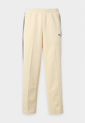 Beige skræddersyede sweatpants med elastisk talje, lynlåslommer i siden, sorte sidelommer og lille mørk Puma-logo på højre lår.