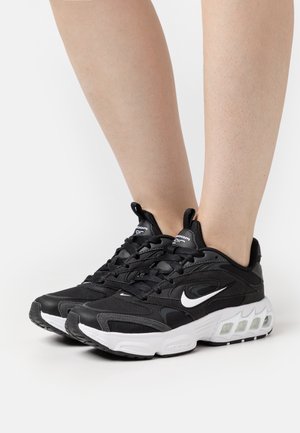 Černé tenisky Nike s prodyšným a syntetickým svrškem, bílými akcenty, polstrovaným límcem a viditelným vzduchovým polstrováním v podrážce.