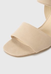 Beez suede sandaalid laia rihmaga peal, millel on lame, lai tall ja sile tekstuur, disainitud mugavuse ja lihtsuse nimel.