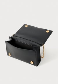 Borsa a mano in pelle nera con bottoni a scatto dorati e catena, aperta per rivelare il compartimento principale e la fodera interna su sfondo bianco.