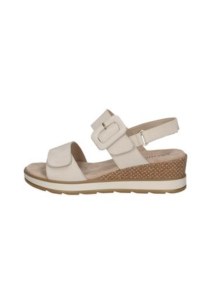 Sandale beige avec un talon compensé, dotée d'une large lanière et d'une boucle réglable. Semelle intérieure douce et texturée, avec des détails en liège à motifs sur le talon.
