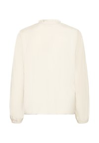 Krämfarbige Bluse mit langen Ärmeln, elastischen Bündchen und einem kleinen Rüschkragen, von hinten auf weißem Hintergrund gezeigt.