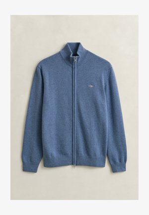 Maglione blu a manica lunga con cerniera integrale, polsini e collo a coste, piccolo logo ricamato sul petto sinistro, disteso su uno sfondo chiaro.