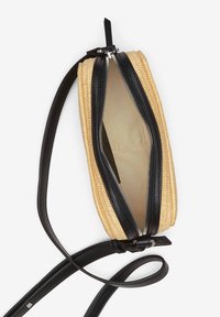 Bolso de paja trenzada con detalles en piel negra, cierre de cremallera y correa ajustable. El interior está forrado con una tela beige clara.