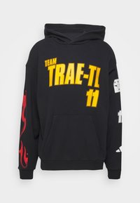 Sweat à capuche noir avec le texte jaune "TEAM TRAE-TL 11" sur le devant, motif de flammes rouges sur la manche gauche, et graphique blanche sur la manche droite.