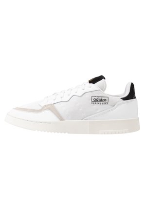 Witte sneakers met een textuurstof, suède accenten en een rubberen zool. Kenmerkt zich door zwarte en beige details en een logo aan de zijkant.