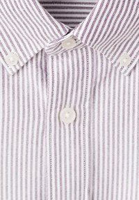 Chemise blanche à rayures violettes, avec un col boutonné, deux boutons au col, et un tissu finement texturé.