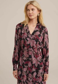 Schwarzes Blumenkleid mit großen rosa und burgunderfarbenen Blumen, langen Ärmeln, einem V-Ausschnitt und einer taillierten Silhouette mit einem Gürteldetail.