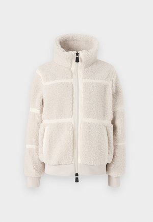 Jachetă din fleece crem cu guler înalt, fermoar frontal, buzunare mari și detalii cu cusături orizontale. Manșete și tiv ribbate. Textură moale.