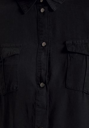 Schwarzes Hemd aus weichem Stoff mit durchgehender Knopfleiste, Kragen und zwei Brusttaschen mit Klappenverschlüssen. Silberne Knöpfe zieren die Vorderseite.