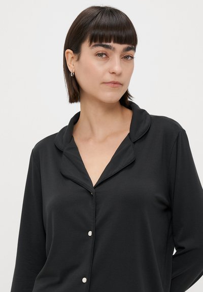 Čierna košeľa na gombíky s mäkkou, ľahkou tkaninou, s klasickým golierom, dlhými rukávmi a bielymi gombíkmi na prednej strane.