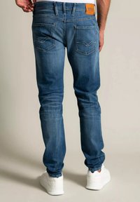 Sinioletut farkut slim fit -mallia, joissa on taustataskut koristeellisin ompelein ja vaaleanruskea nahkaleima vyötäröllä. Yhdistetty valkoisiin tennareihin.