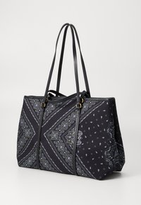 Grote zwarte draagtas met paisley- en geometrische patronen in wit en groen, voorzien van lange dubbele handvatten en gouden ringen.